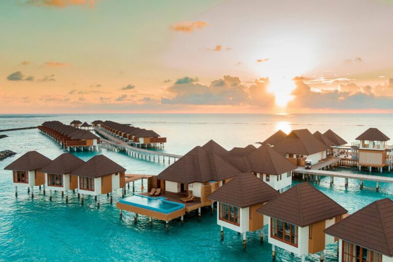 Maldives tropical island with overwater villas, clear blue water and white sand beach
